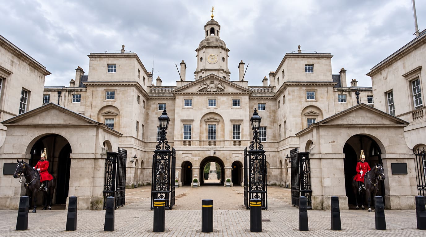 Two mounted guards in red tunics and plumed helmets sit on black horses in the sentry arches at Horse Guards in London on an overcast day.